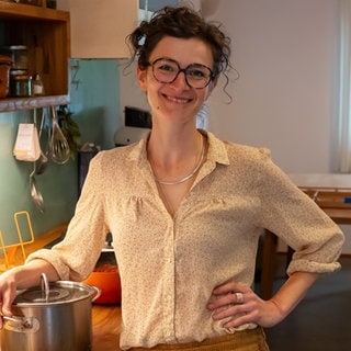 Junge Frau in der Küche neben einem Kochtopf