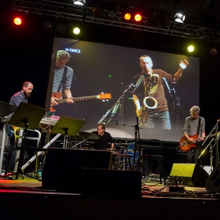 Musiker auf der Bühne, mit Videoprojektion