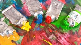 Fünf geöffnete Farbtuben auf buntem Papier