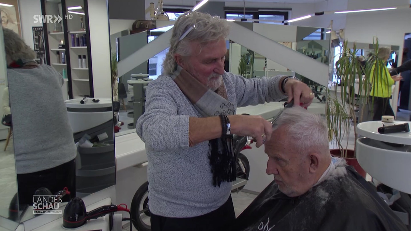 Friseur Eric Schraepel schneidet einem Kunden die Haare